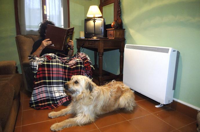 Persona leyendo con la luz encendida, al lado de la calefacción.