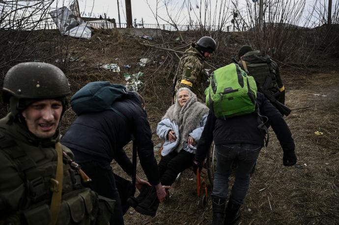 Varios soldados ucranianos ayudan a evacuar a una anciana en Irpín.