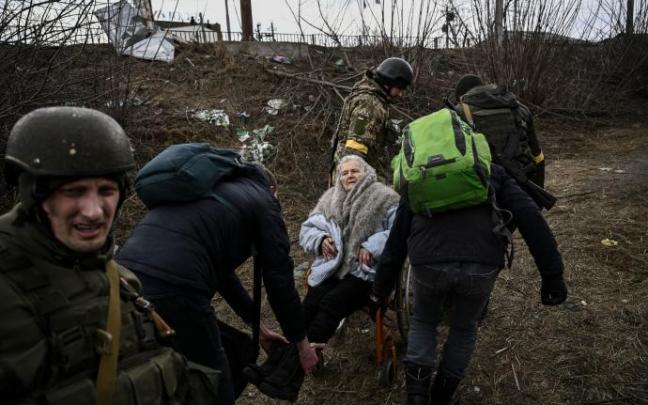 Varios soldados ucranianos ayudan a evacuar a una anciana en Irpín.
