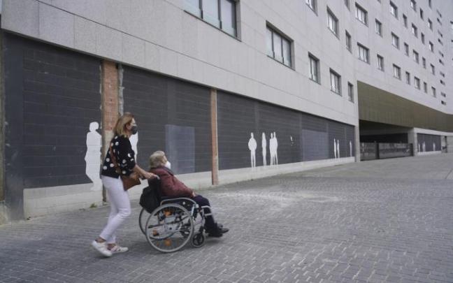 Una persona mayor en silla de ruedas junto a su cuidadora paseando por Vitoria