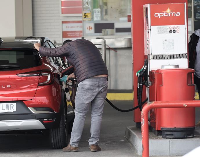 Una persona recarga combustible en una gasolinera.