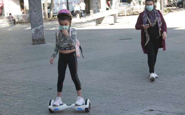 Personas andando por la calle con mascarillas.