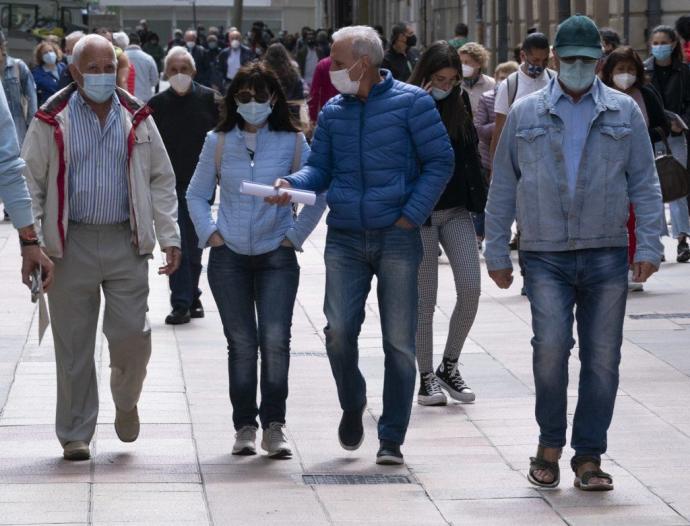 Personas andando por Vitoria con mascarilla.