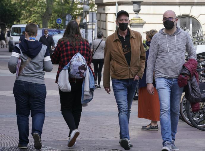 Personas andando por la calle con mascarilla.