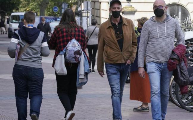 Personas andando por la calle con mascarilla.