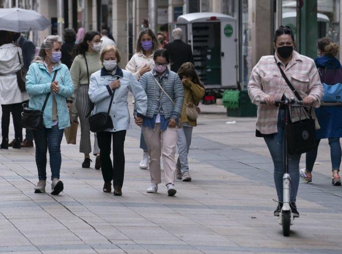 Personas paseando por el centro de Vitoria con mascarilla.