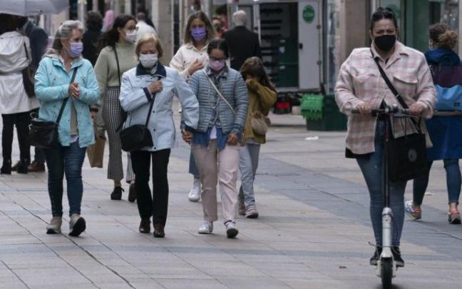 Personas paseando por el centro de Vitoria con mascarilla.