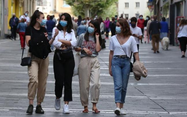 Varias personas caminan hablando por la calle.