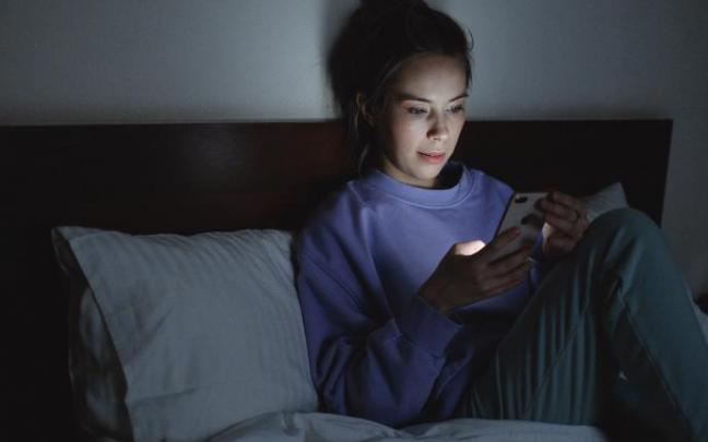 El adolescente simula que está dormido en su habitación, pero realmente está con el móvil.