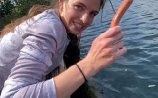 La joven, dispuesta a ofrecer una salchicha a los peces.