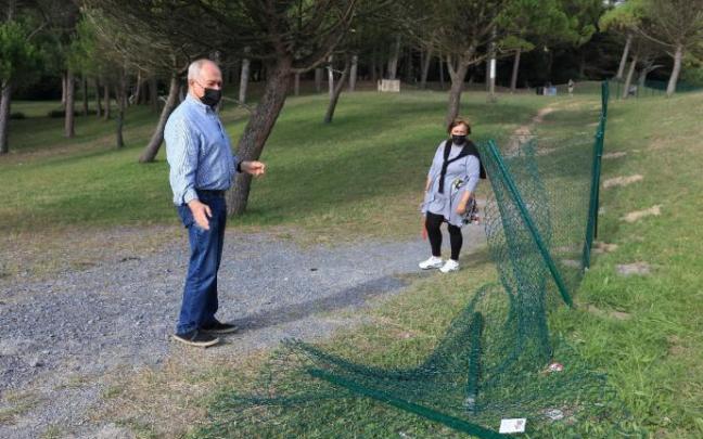 Dos vecinos observan la parte derribada de la valla que se puso el pasado verano para controlar los accesos al pinar.