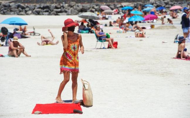 Una mujer se quita la mascarilla al llegar a la playa