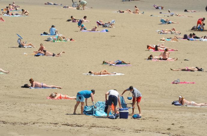 Varias personas disfrutan de la playa.