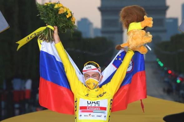 Tadej Pogacar, envuelto en la bandera de Eslovenia en el podio de los Campos Elíseos, celebra la victoria en el Tour.