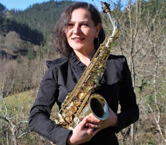 Elsa García con su saxofón y el bello paraje rural de Zeberio, donde vive, al fondo.