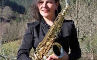 Elsa García con su saxofón y el bello paraje rural de Zeberio, donde vive, al fondo.