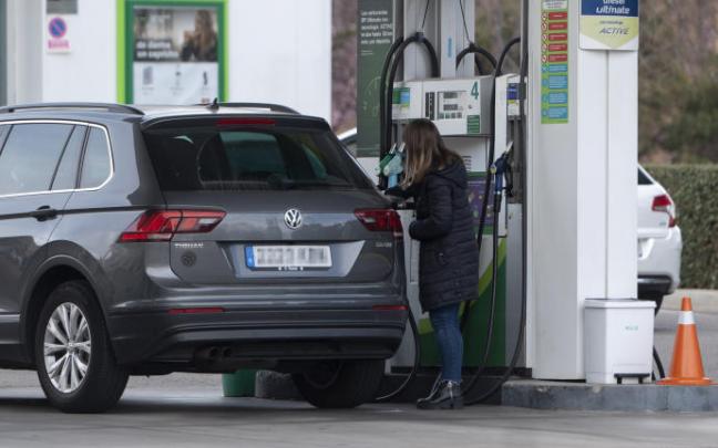 Una mujer reposta combustible en una gasolinera. Una mujer reposta combustible en una gasolinera.