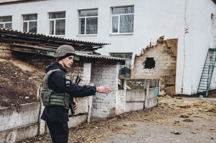 Un policía da instrucciones frente a una guardería donde ha impactado un proyectil en Stanitsa Luganska.