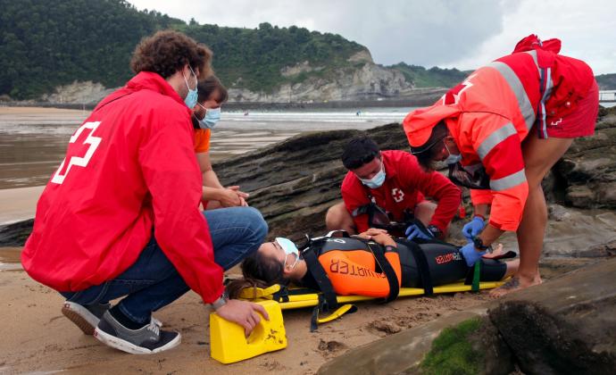 Socorristas inmovilizan a una joven indispuesta en la playa de Plentzia para trasladarla al puesto de socorro.