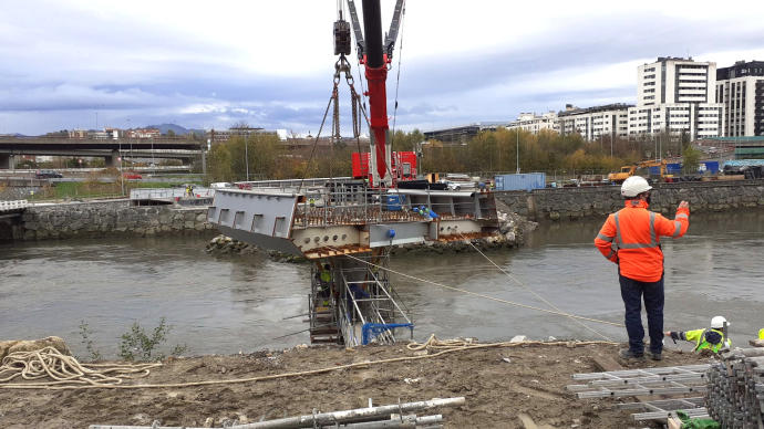 La pieza colgada de la grúa se coloca sobre una de las pilas del puente, en el lado de Egia.