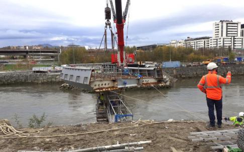 La pieza colgada de la grúa se coloca sobre una de las pilas del puente, en el lado de Egia.