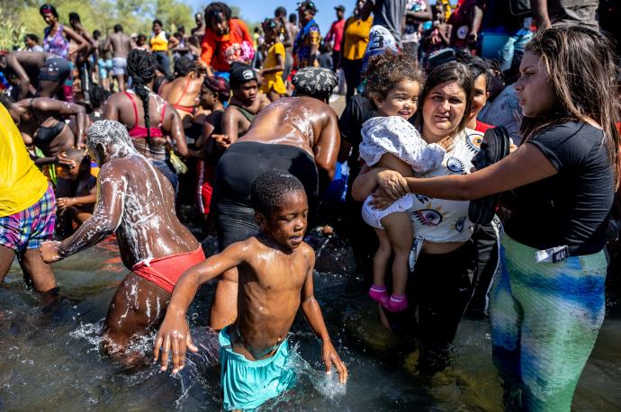Un grupo de migrantes se lavan bajo el puente de Del Río