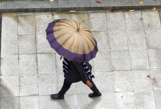 Una persona se protege de la lluvia mientras caminan por una céntrica zona de Bilbao.
