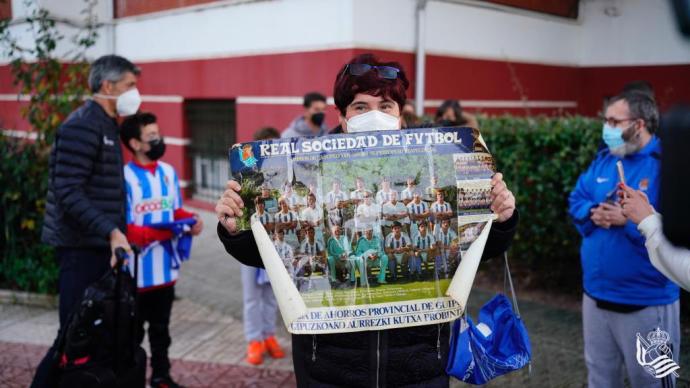 Una aficionada muestra un póster histórico de la Real mientras Imanol se hace una foto con otros aficionados a la salida del hotel de Zamora.