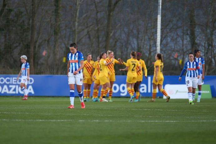 Las jugadoras de la Real, cabizbajas, con las del Barça celebrando unos de los nueve goles marcados en Zubieta