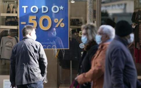 Varias personas frente a una tienda que ofrece rebajas. Varias personas frente a una tienda que ofrece rebajas.