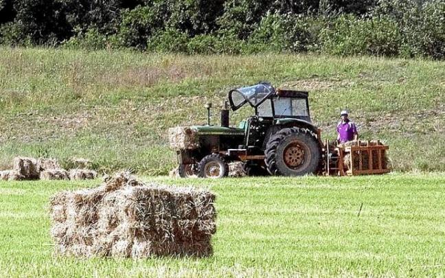Un agricultor haciendo fardos de paja con un tractor. Foto: Josu Chavarri