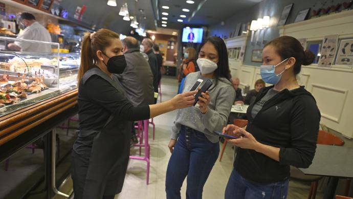 Una trabajadora pide el pasaporte covid a unas clientas en un bar de Bilbao.