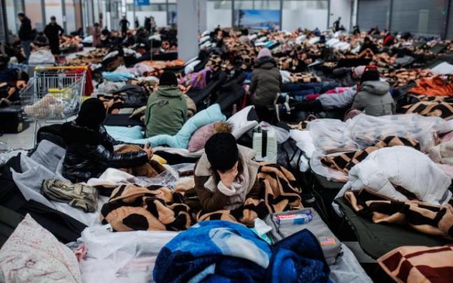 Varias personas descansan en un centro comercial destinado a la acogida temporal de los refugiados, Polonia.