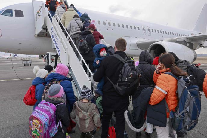 Un grupo de refugiados ucranianos hacen cola para subir a un avión.