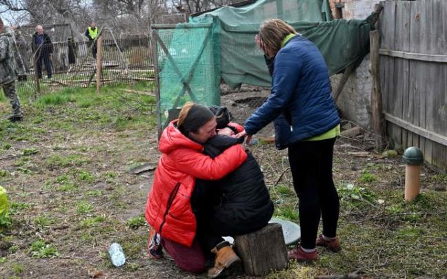Varias personas lloran tras hallar el cuerpo de un familiar en el patio de su casa, Kiev.