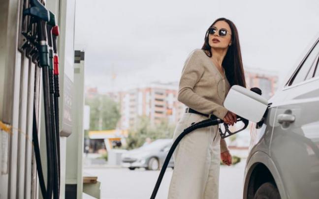 Una mujer echa gasolina a su coche en una estación de servicio.