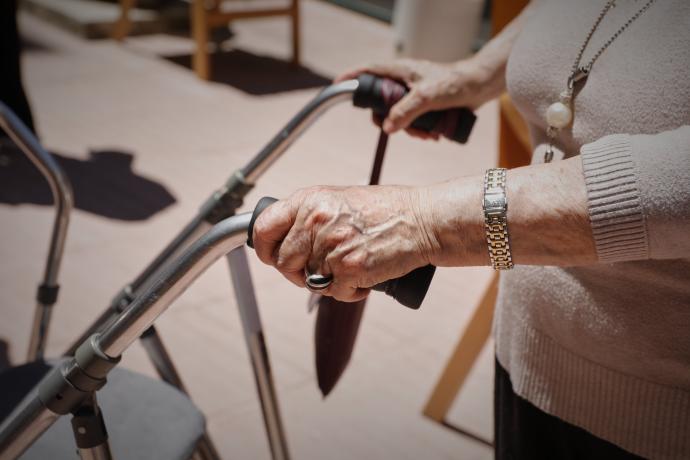 Una persona mayor se desplaza con una andador en una residencia.