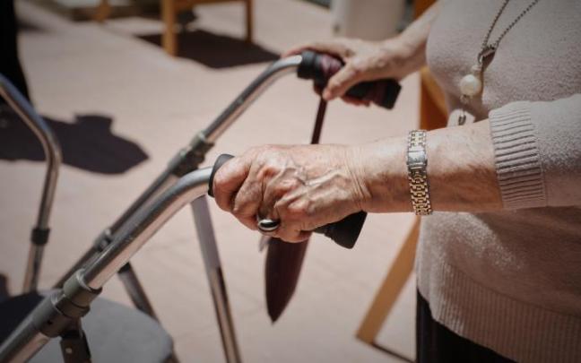 Una persona mayor se desplaza con una andador en una residencia.