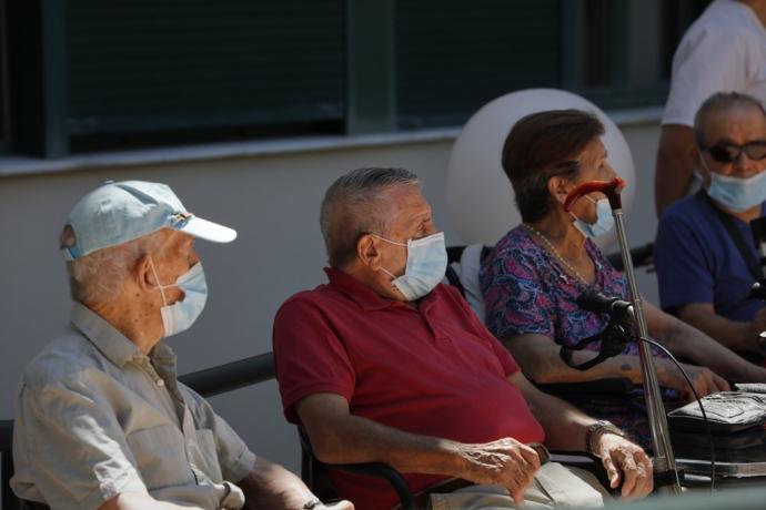 Usuarios de una residencia de mayores sentados en un banco.