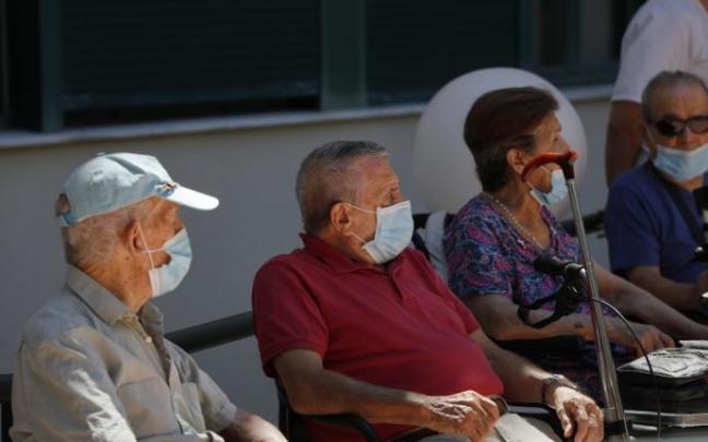 Usuarios de una residencia de mayores sentados en un banco.