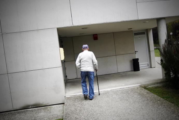 Un hombre mayor se aproxima a su residencia.