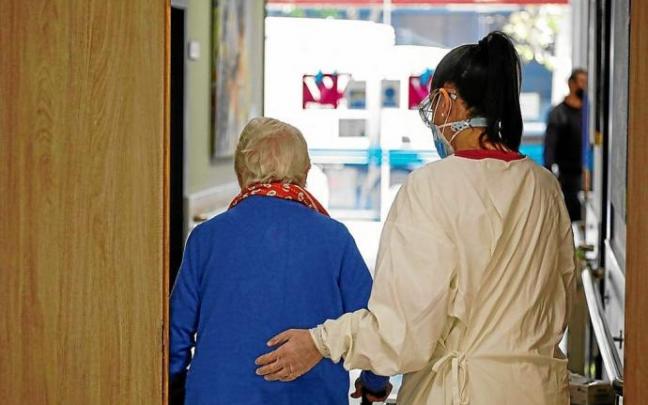 Una persona residente en un geriátrico es acompañada por su cuidadora. Foto: Efe