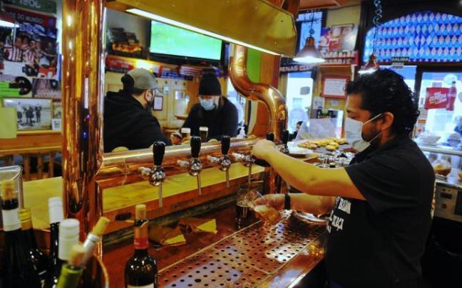 Un camarero atiende a unos clientes en el interior de un bar.