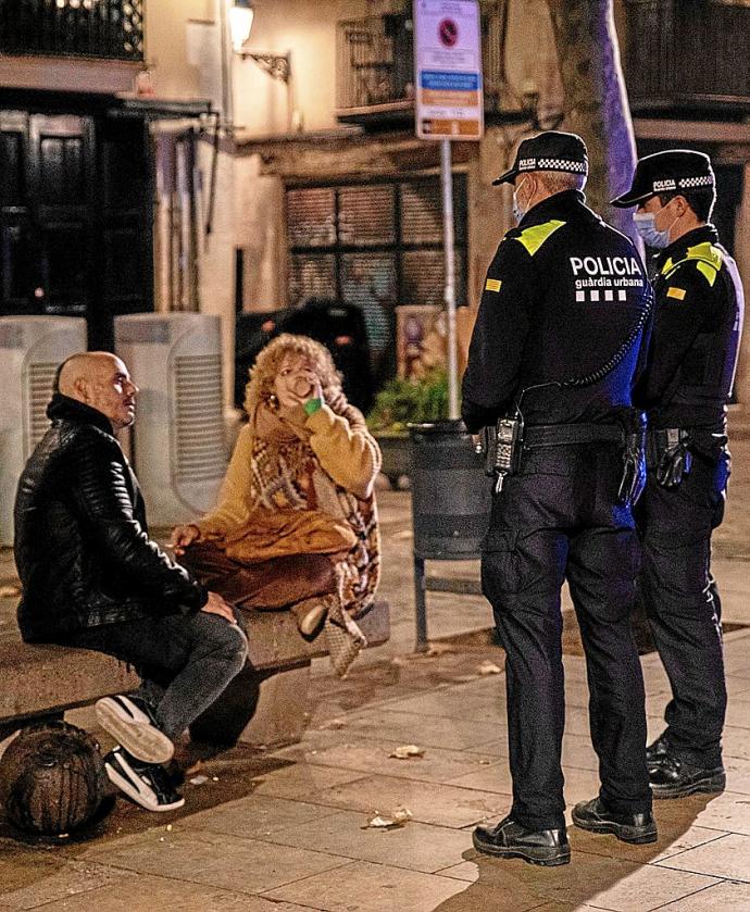 Dos policías informan a una pareja de la implantación del toque de queda en Barcelona. Foto: E. P.