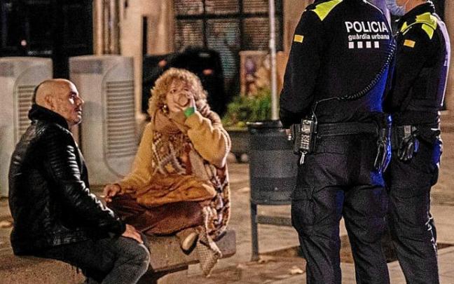 Dos policías informan a una pareja de la implantación del toque de queda en Barcelona. Foto: E. P.