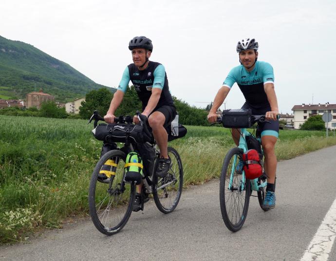 Antton Zelaia Etxarri y Mikel Astiz Erro prueban la bici con el equipaje que van a llevar en la carretera de Urdiain.