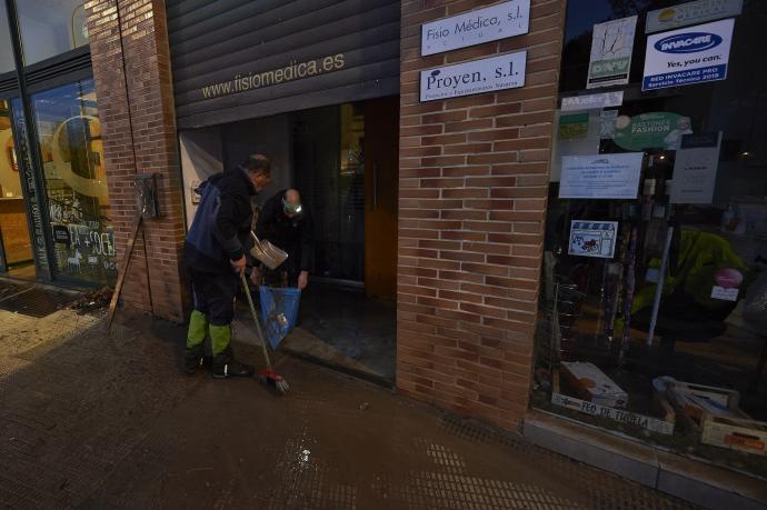 Un vecino limpiando un comercio de la Rochapea