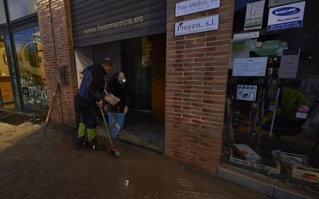 Un vecino limpiando un comercio de la Rochapea