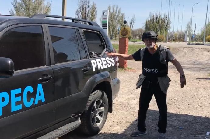El periodista de Radio Nacional Fran Sevilla, mostrando los daños de su vehículo segundos antes de que se escuchara un nuevo proyectil.