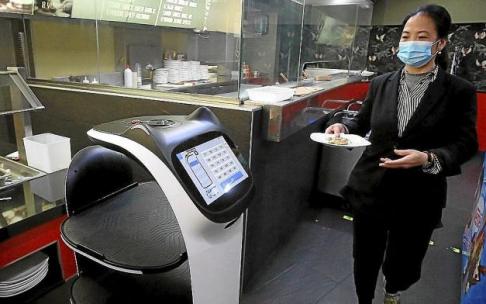Una trabajadora del restaurante lleva al robot un plato de comida.